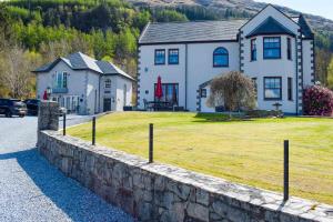 una casa con una pared de piedra frente a un patio en Outlander Glencoe at Creag an-t Sionnaich, en Glencoe