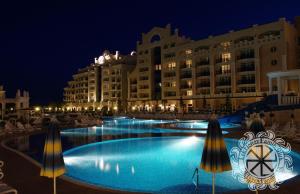 una grande piscina di fronte a un edificio di notte di Apartment Sunset Resort a Pomorie