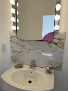ein Waschbecken mit einem Spiegel darüber in der Unterkunft Appartement au calme et bow window quartier plage in Mers-les-Bains