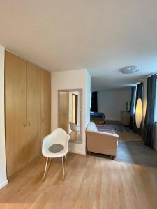 a living room with a white chair and a mirror at Altstadtwohnung - Old Town in Trostberg an der Alz +33 photos
