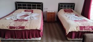 two beds in a room with red and white sheets at Hotel Baykal in Bogazkale