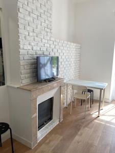 sala de estar con mesa y TV en la chimenea en LA MAISON D'ANTONIN 2 en Nimes