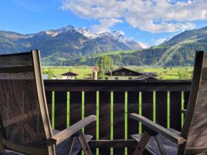 a pair of chairs sitting on a balcony with mountains at Mountain View near Kaprun - Steinbock Lodges in Piesendorf