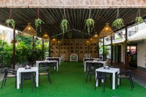 a restaurant with white tables and chairs and plants at Hotel The Enchanted Residence in Dhaka