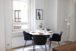 une salle à manger blanche avec une table et des chaises dans l'établissement 2ndhomes Cozy Courtyard home with Sauna in Kruununhaka, à Helsinki