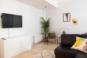 a living room with a black couch and a flat screen tv at ---2ndhomes Cozy Courtyard home with Sauna in Kruununhaka--- in Helsinki