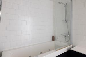 a bath tub with a glass shower stall in a bathroom at ---2ndhomes Cozy Courtyard home with Sauna in Kruununhaka--- in Helsinki +14 photos