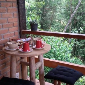 una mesa con tazas y platillos en el balcón en Chalé Samasati, en Visconde De Maua