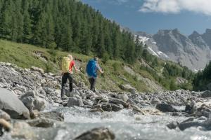 two people walking across a stream of rocks at Hotel Nevada in Samnaun