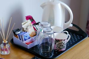 uma bandeja com um bule de chá e chávenas numa mesa em Upton Village Guest House em Birkenhead