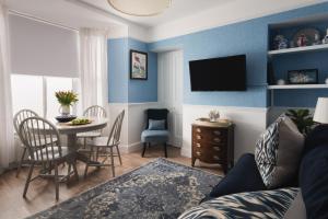 Sala de estar azul con mesa y TV en One Sandringham - Boutique Seaside Home in Ilfracombe, en Ilfracombe