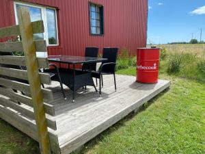 a wooden deck with a table and chairs and a trash can at Villa Sandby B&B in Borrby