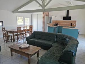 a living room with a green couch and a table at AUBERGE LE GABACHOU in Montpezat-de-Quercy