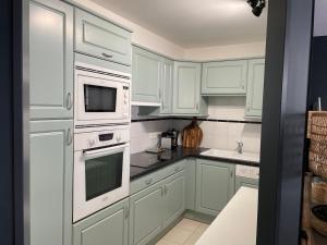 a kitchen with white cabinets and white appliances at La Parenthèse Touquettoise in Le Touquet-Paris-Plage