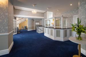 a lobby with blue carpeting and a staircase in a building at Hotel Rex in Weymouth