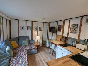 een woonkamer met een bank en een tafel en een keuken bij Cobweb Cottage in Spooner Row