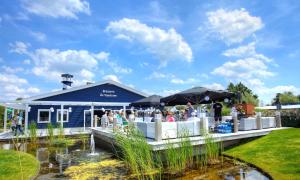 a blue building with people standing on a bridge over a pond at EuroParcs Bad Hulckesteijn in Nijkerk