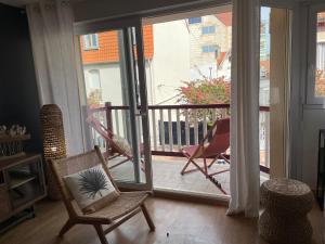 uma sala de estar com uma porta aberta para uma varanda em La Parenthèse Touquettoise em Le Touquet-Paris-Plage