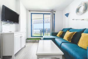 塔烏里托的住宿－Home2Book Valle de Taurito, Sea Views & Pool，客厅配有蓝色的沙发和电视