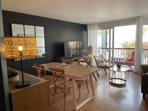 uma sala de estar com uma mesa de madeira e cadeiras em La Parenthèse Touquettoise em Le Touquet-Paris-Plage