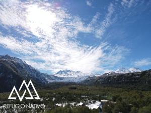 uma vista para um vale montanhoso com montanhas cobertas de neve em Refugio Nativo em Nevados de Chillan