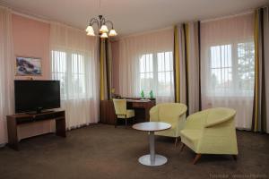 a living room with a tv and chairs and a table at Hotel Zámeček in Poděbrady