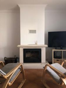 a living room with two chairs and a fireplace at PÉ NA AREIA by Stay in Alentejo in Vila Nova de Milfontes