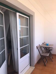 une porte donnant sur un balcon avec une table et une chaise. dans l'établissement PÉ NA AREIA by Stay in Alentejo, à Vila Nova de Milfontes