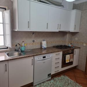 una cocina con armarios blancos y fregadero en PÉ NA AREIA by Stay in Alentejo, en Vila Nova de Milfontes