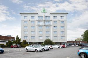 un gran edificio blanco con coches aparcados en un aparcamiento en Holiday Inn Basildon, an IHG Hotel en Basildon