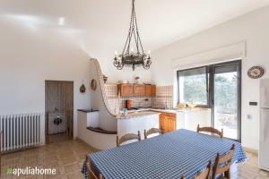 une cuisine et une salle à manger avec une table et un lustre dans l'établissement Emma's Villa fronte mare con piscina, à Torre Suda