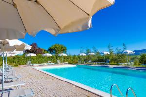 a swimming pool with umbrellas and chairs and a pool at Glamping Gli Etruschi in Piombino