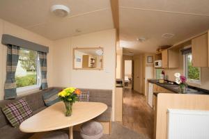 a living room and kitchen with a vase of flowers on a table at Golden Sands Holiday Park in Kinmel Bay