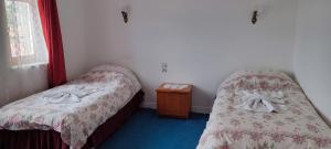 um quarto com duas camas e uma mesa de cabeceira em Hotel Baykal em Bogazkale