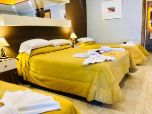 three beds in a room with towels on them at Hotel Villa Santa Maiani in Mar del Plata +130 photos