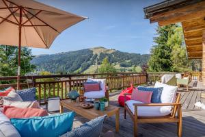 a deck with chairs and an umbrella and a table at Chalet Joux Verte - OVO Network in Les Gets