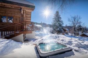 a hot tub in the snow next to a cabin at Chalet Joux Verte - OVO Network in Les Gets