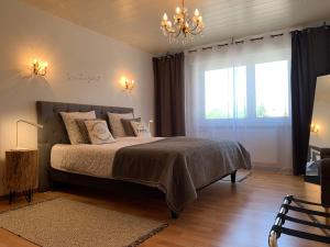 a bedroom with a bed with a chandelier and a window at Gîte du cerf in Birkenwald