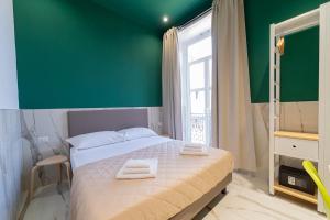 Un dormitorio con una pared verde y una cama con toallas. en P.C. Boutique Medina H. Napoli Centro, by Clapa Group en Nápoles