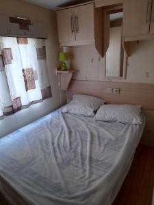een bed met 2 kussens in een kamer bij Mobil home - Clim, LL, TV - Camping Le Lac des Rêves '4 étoiles' - 001 in Lattes