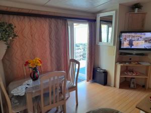 a dining room with a table and a television at Mobil home - Clim, LL, TV - Camping Le Lac des Rêves '4 étoiles' - 001 in Lattes