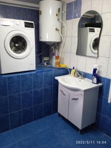 a blue tiled bathroom with a washing machine and a sink at Central city house in Tulcea