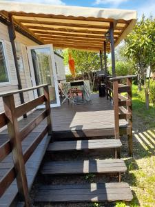 une terrasse en bois avec pergola sur une maison dans l'établissement Mobil home - Clim, LL, TV - Camping Le Lac des Rêves '4 étoiles' - 001, à Lattes