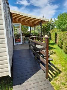 une terrasse en bois avec pergola à côté d'une maison dans l'établissement Mobil home - Clim, LL, TV - Camping Le Lac des Rêves '4 étoiles' - 001, à Lattes