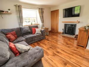 sala de estar con sofá y chimenea en Borders Cottage en Jedburgh