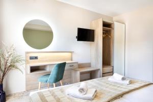 1 dormitorio con cama, silla y espejo en Elena Beach Hotel en Kíssamos