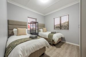 two beds in a room with two windows at Beacon Wharf , George Hay 6 Seafront Accommodation in Mossel Bay