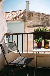 einen Stuhl auf einem Balkon mit Tisch und Topfpflanzen in der Unterkunft Nomad Dreams N2 in Cascais