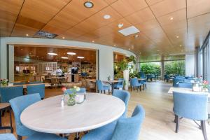 a dining room with a table and blue chairs at WestCord ApartHotel Boschrijck in West-Terschelling