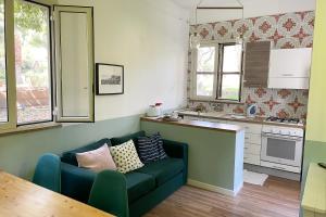 sala de estar con sofá verde en la cocina en Villa Caterina - Solemar Sicilia, en Cefalú